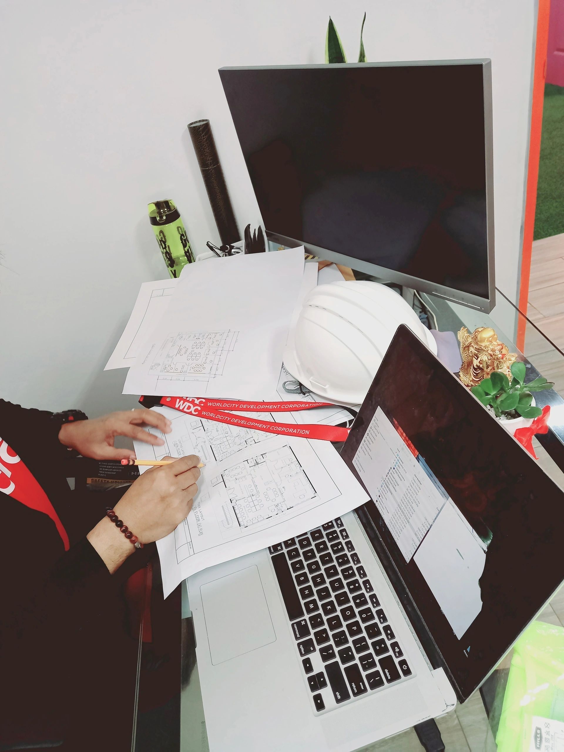 Construction drawings, a hard hat and laptops at a Worldcity workspace